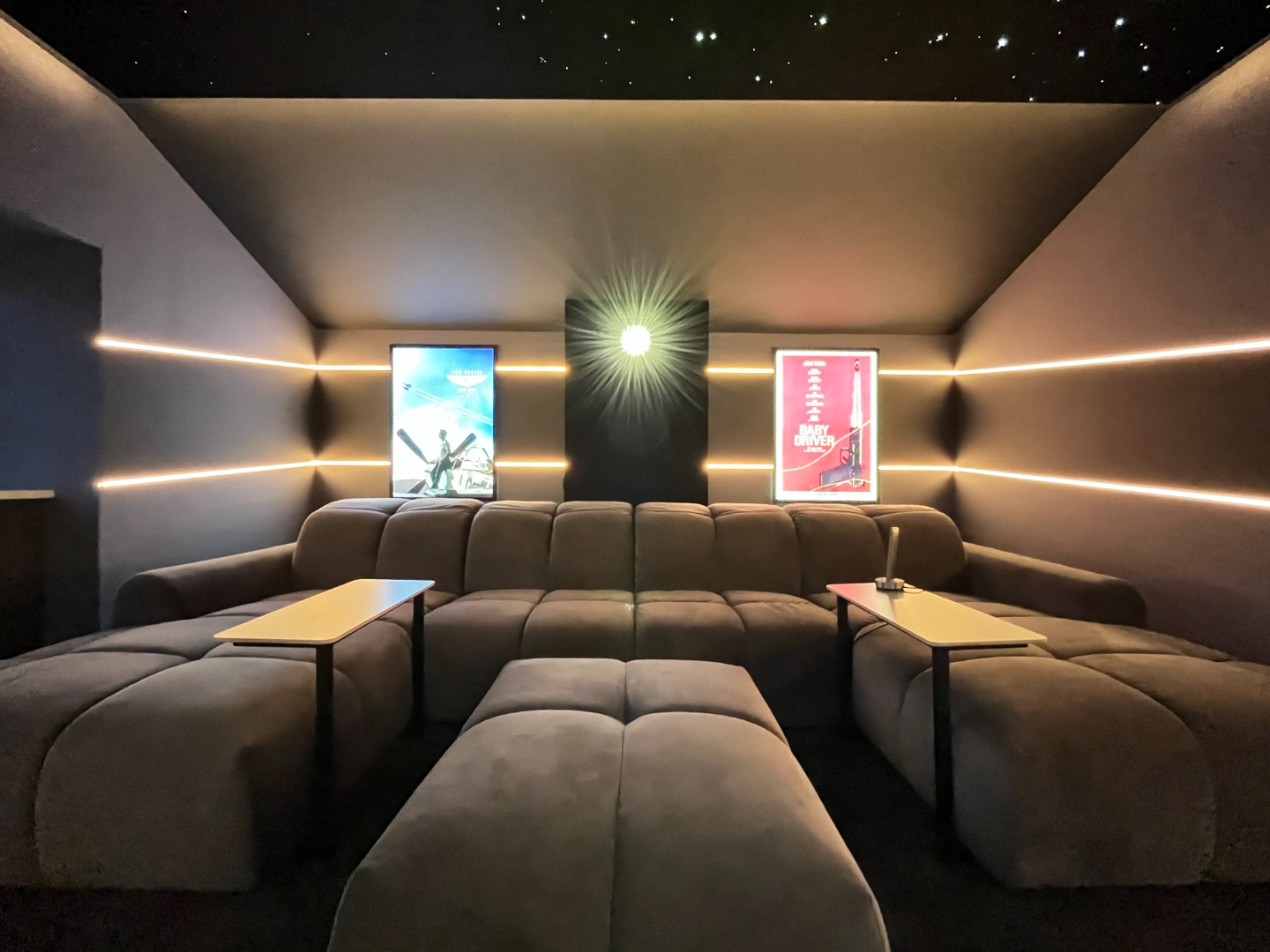 Front-on view of private cinema with star ceiling, film posters and modular seating